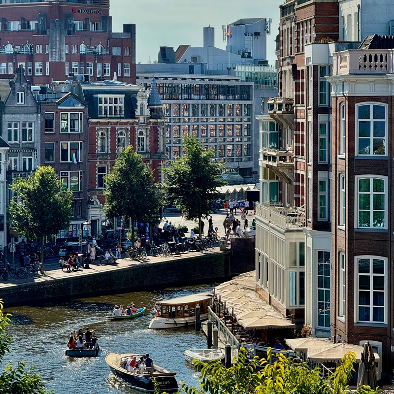 Amsterdam canal houses view with a canal busy with boat tours and excursions